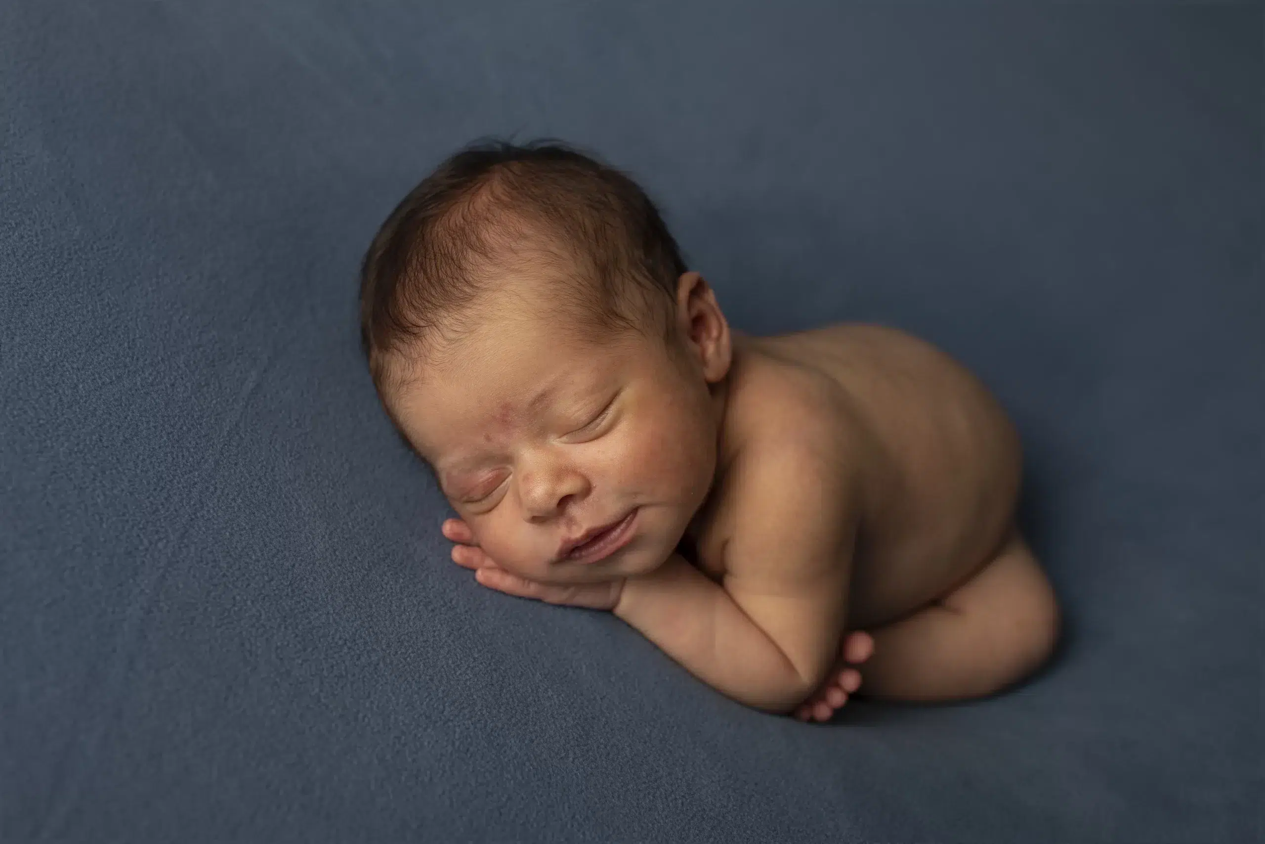 Transforme suas fotos com uma pós-produção humanizada e profissional 3 Bebê recém-nascido dormindo em posição fetal, capturado antes da pós-produção
